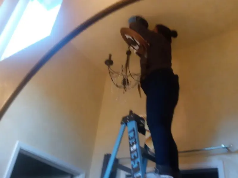 Electrician installing a chandelier in a St. Joseph residence